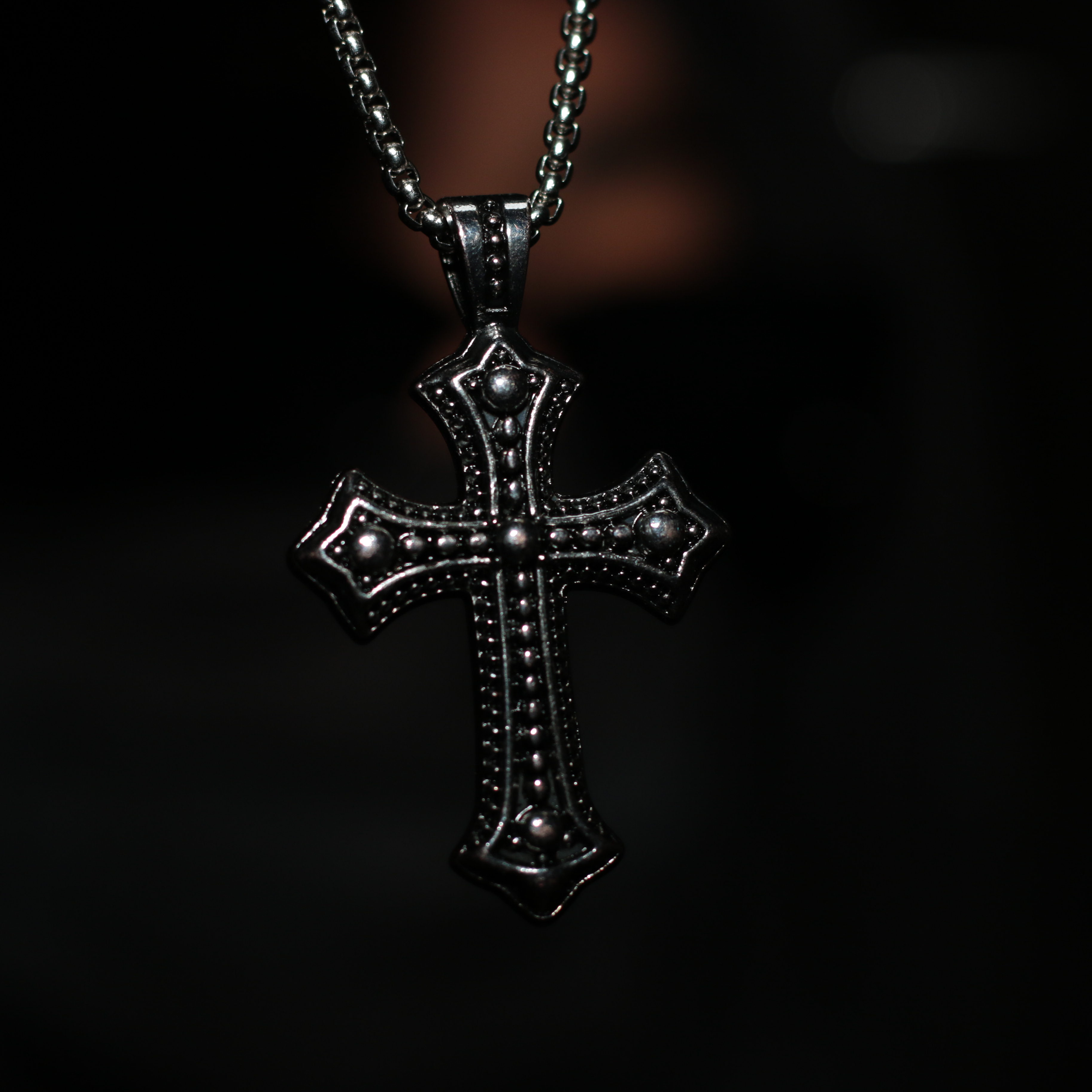 Silver cross pendant on a dark background